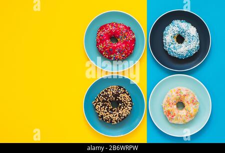 Quatre beignets appétissants se trouvent sur des plaques en céramique couleur. Banque D'Images