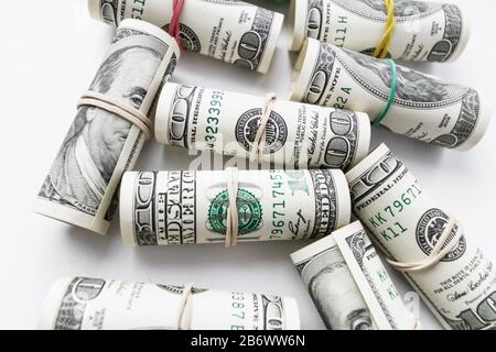 Les billets de cent dollars américains se sont enroulés sous forme de tubules. Fond clair, gros plan, mise au point sélective Banque D'Images