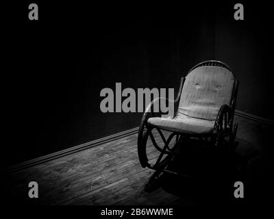 Chaise rocking en osier dans une chambre vide avec parquet, style minimaliste monochrome Banque D'Images