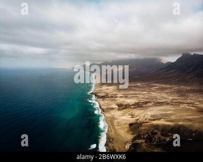 Vue aérienne de la longue plage de Cofete à Fuerteventura avec de l'eau bleue et des montagnes désertes Banque D'Images