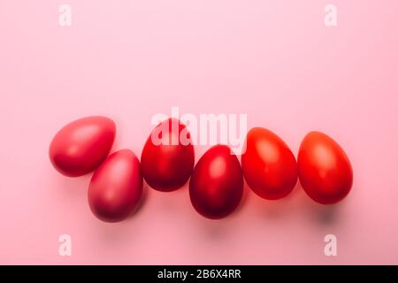 Pâques six oeufs rouges en ligne sur fond rose. Concept festif. Style plat. Banque D'Images