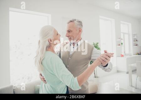 Portrait de belles personnes mariées tenir les mains se déplaçant dans la maison d'appartement vêtu de sauteurs brun teal Banque D'Images