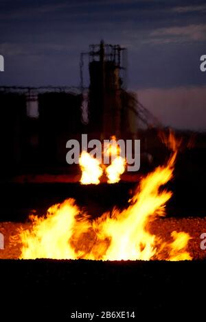 Torchage de gaz près d'une plate-forme pétrolière et de réservoirs de stockage à l'extérieur de Williston au Dakota du Nord. La région fait partie du champ pétrolier de Bakken, où la technologie de fracking l'a rendu rentable tant que le prix du pétrole reste supérieur à 46 USD le baril. Banque D'Images