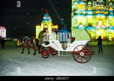 Un cheval et une voiture emmène les touristes à travers Snow & Ice World à Harbin. Banque D'Images