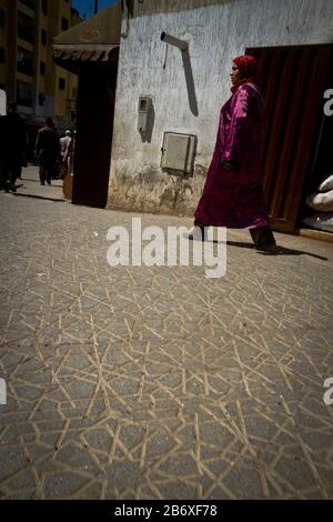 Une femme dans une robe colorée traverse les rues de Fes, au Maroc Banque D'Images