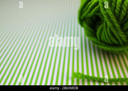 Boule de fil vert sur un fond rayé vert. Banque D'Images