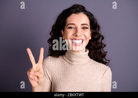 Gros plan photo séduisante incroyable, elle sa dame qui se beaming tiothy sourire main bras doigts v-signe symbole positif gai dire bonjour amis porter décontracté Banque D'Images