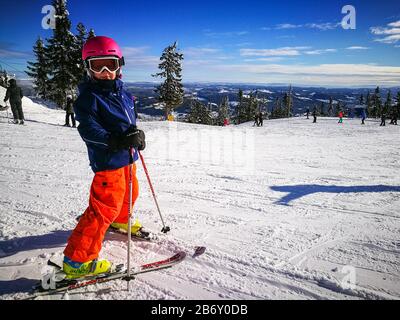 Jeune fille en tenue de ski colorée prête à skier les pistes de slalom de la station de ski de Trysilfjellet en Norvège Banque D'Images