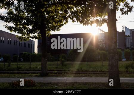 Un cadre de soleil derrière un immeuble de bureaux avec des arbres devant Banque D'Images