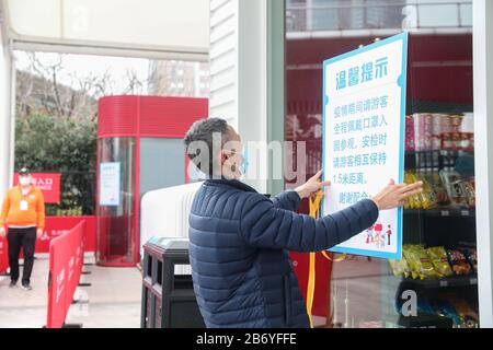 Shanghai. 12 mars 2020. Un membre du personnel affiche des informations sur les réductions de billets à l'entrée de la tour des perles orientales de Shanghai, dans l'est de la Chine, le 12 mars 2020. La tour de Shanghai, le bâtiment le plus élevé de Chine, a rouvert son attraction touristique « Top of Shanghai Observatory » à partir de jeudi. Deux autres sites touristiques ont également commencé à recevoir des touristes de jeudi, dont la tour des perles orientales de Shanghai et la tour Jinmao de Shanghai. POUR ALLER AVEC les paysages de gratte-ciel de 'Hanghai, les monuments à rouvrir' crédit: Ding Ting/Xinhua/Alay Live News Banque D'Images