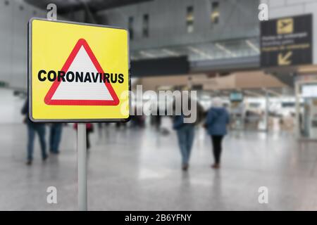 Panneau d'avertissement avec texte Coronavirus sur un aéroport terminal générique avec les passagers marchant vers les portes d'embarquement. Concept de crise du coronavirus Banque D'Images