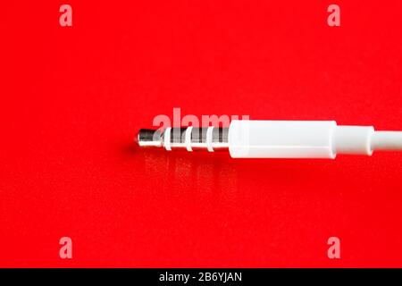 Connecteur blanc câble blanc auxiliaire sur fond rouge Banque D'Images