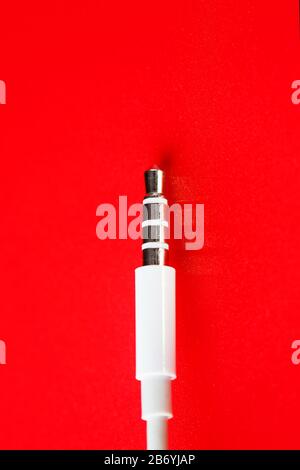 Connecteur blanc câble blanc auxiliaire sur fond rouge Banque D'Images