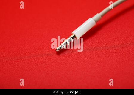 Connecteur blanc câble blanc auxiliaire sur fond rouge Banque D'Images