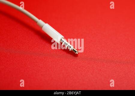 Connecteur blanc câble blanc auxiliaire sur fond rouge Banque D'Images