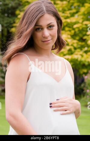 Belle jeune femme enceinte caressant son bosse de bébé Banque D'Images