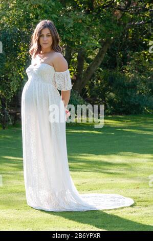 Belle jeune femme enceinte portant une longue robe blanche, cachant son bébé bosse Banque D'Images