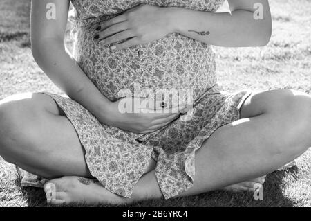 Noir et blanc, image rapprochée de la femme enceinte qui caresse son bébé bosse Banque D'Images