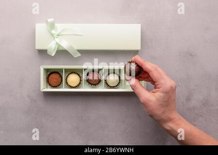 Une fille tient une boîte de chocolats sur un fond gris. Vue du dessus de la présentation à plat. Espace de copie de cadre horizontal Banque D'Images