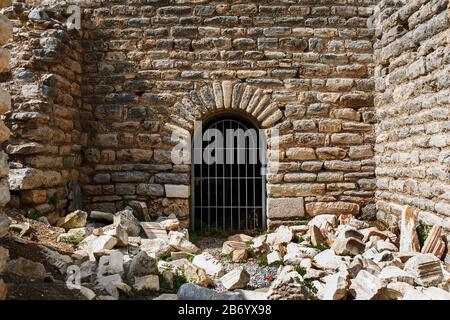 La porte est de la grille métallique d'un ancien bâtiment ancien, un château de pierre avec des blocs tentaculaires. Les ruines de l'antiquité Banque D'Images