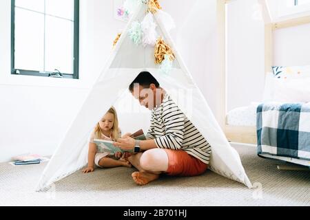 Gros plan portrait d'un père et d'un enfant lisant ensemble dans la chambre d'un enfant Banque D'Images