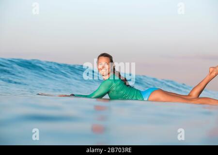 Jeune femme souriante couché sur une planche de surf Banque D'Images