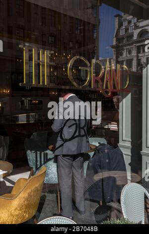 Vu de travers la fenêtre, un client masculin se prépare à quitter sa place dans le Grand café sur Piccadilly, l'ombre de son nom, un endroit élégant et prestigieux pour manger et boire à Mayfair, imprimé sur son dos, le 6 mars 2020, à Londres, en Angleterre. Banque D'Images