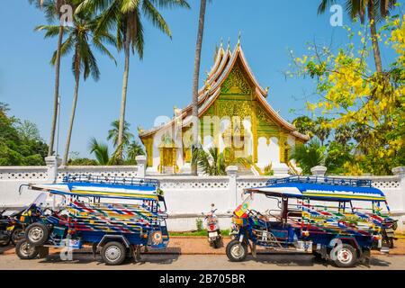 Tuk-tuks colorés devant le temple de Haw Pha Bang sur le terrain du Musée du Palais Royal à Luang Prabang, province de Louangphabang, Laos Banque D'Images