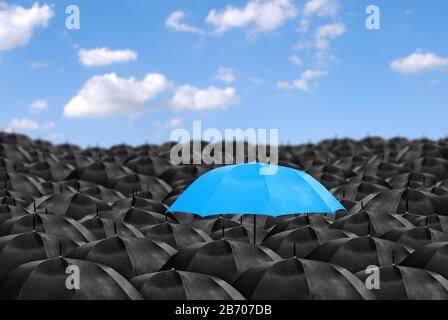 Parapluie coloré dans la masse des parapluies noirs. Banque D'Images