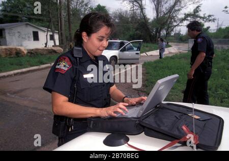 Austin, Texas États-Unis: Femme hispanique policier utilisant un ordinateur portable pour remplir les rapports sur le terrain. M. ©Bob Daemmrich Banque D'Images