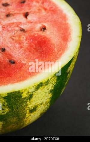 Moitié de pastèque rouge mûre et savoureuse sur fond noir, texture de la pâte juteuse de pastèque rouge mûre avec des graines Banque D'Images