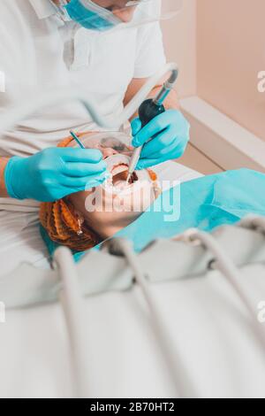 Le patient visite le dentiste au sujet de la procédure de nettoyage ultrasonique des dents en dentisterie.2020 Banque D'Images