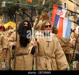 Rijeka, Croatie, 23 février 2020. Homme et femme déguisés en costumes de prêtres médiévaux et vêtus de robes en jute avec un grand crucifix sur la poitrine Banque D'Images