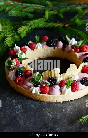 Tarte savoureuse avec crème à l'air, confiture de baies, baies fraîches, meringue et menthe sur un fond sombre. Délicieuse tarte aux baies sauvages mûres. Chef français gastronomique Banque D'Images