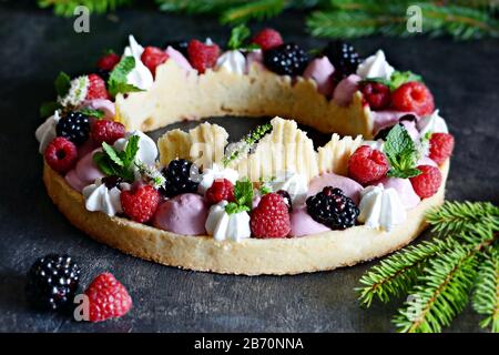 Tarte savoureuse avec crème à l'air, confiture de baies, baies fraîches, meringue et menthe sur un fond sombre. Délicieuse tarte aux baies sauvages mûres. Chef français gastronomique Banque D'Images