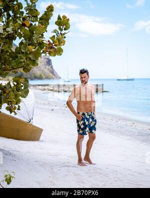 Jeunes hommes en maillot de bain, Sugar Beach Sainte-Lucie, une plage tropicale blanche publique avec palmiers et chaises de plage de luxe sur la plage de l'île St Banque D'Images