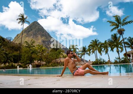Jeunes hommes en maillot de bain, Sugar Beach Sainte-Lucie, une plage tropicale blanche publique avec palmiers et chaises de plage de luxe sur la plage de l'île St Banque D'Images