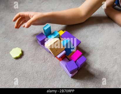 Un enfant joue avec un coeur coloré avec des blocs de construction en bois colorés. Concept de journée mondiale de sensibilisation à l'autisme. Banque D'Images