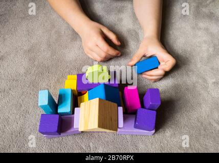Un enfant joue avec un coeur coloré avec des blocs de construction en bois colorés. Concept de journée mondiale de sensibilisation à l'autisme. Banque D'Images