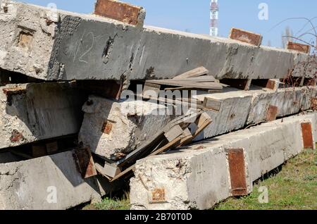 Piles de béton utilisées à l'extérieur. Un groupe d'anciens produits en béton armé empilés l'un sur l'autre. Réutilisation des matériaux de construction. Mise au point sélective. Banque D'Images