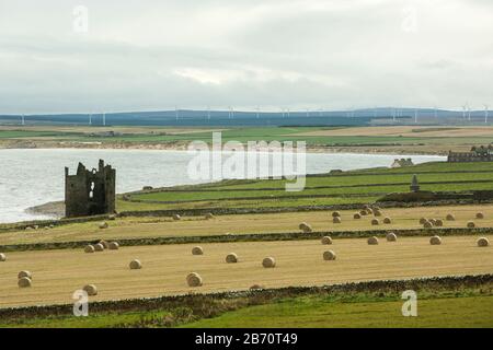 Le château de Keiss se trouve dans des ruines au milieu de champs de cultures avec des moulins à vent en arrière-plan, à Sinclairs Bay, Reiss Beach, près de Wick, Caithness, Écosse Banque D'Images