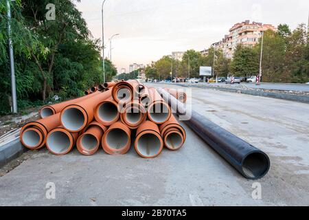 Pipeline PVC empilé sur la route, construction de route avec tuyaux Banque D'Images