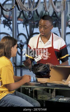 Round Rock, Texas Etats-Unis: Une jeune fille de 13 ans qui retourne un casque de vélo pour le magasin où un jeune employé de Black l'aide. M. ©Bob Daemmrich Banque D'Images