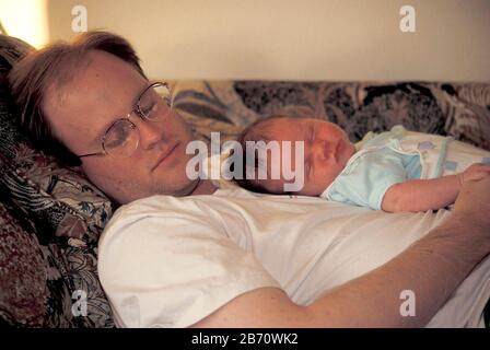 Austin Texas USA: Bébé de trois semaines dormant avec papa sur le canapé. M. ©Bob Daemmrich Banque D'Images