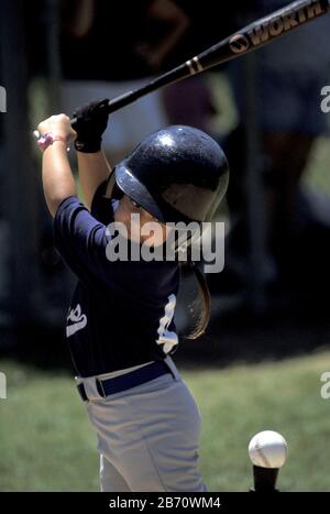 Austin, Texas États-Unis : le jeune batter prend un swing avec sa batte à la balle assise sur le tee-shirt pendant le match de ligue de T-ball pour les garçons et les filles de cinq et six ans. M. ©Bob Daemmrich Banque D'Images