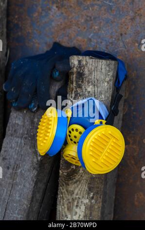 Le respirateur et les gants de travail sont suspendus sur les panneaux. Masque jaune-bleu et gants bleu marine. Équipement de protection individuelle. Mise au point sélective. Sho Banque D'Images