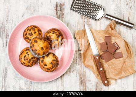 Cupcakes avec copeaux de chocolat sur une plaque rose sur une table en bois Banque D'Images