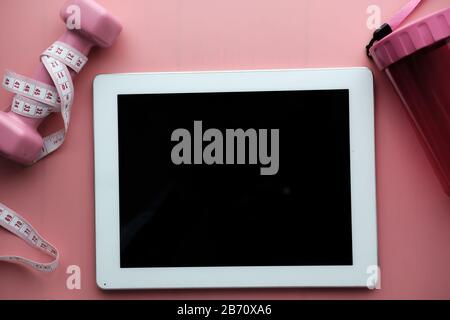 vue de dessus de la tablette numérique et de la haltère sur fond rose Banque D'Images