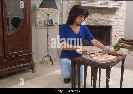 Femme présentant un trouble obsessionnel-compulsif en redressant la table à café dans son salon. ©Bob Daemmrich Banque D'Images