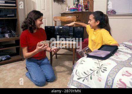 Austin Texas USA: 15-ans-filles hispaniques écoutant des CD à la maison. M. ©Bob Daemmrich Banque D'Images